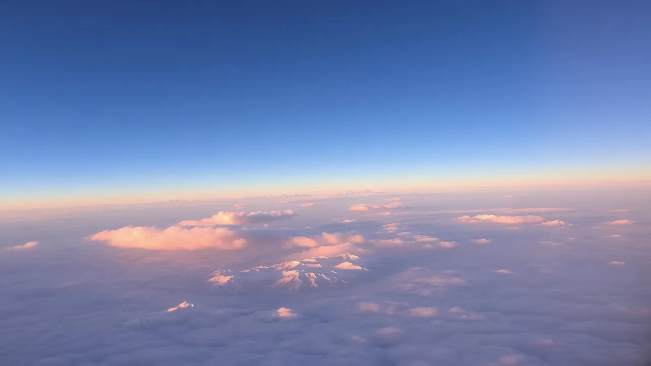 View from an airplane window above the clouds at sunrise